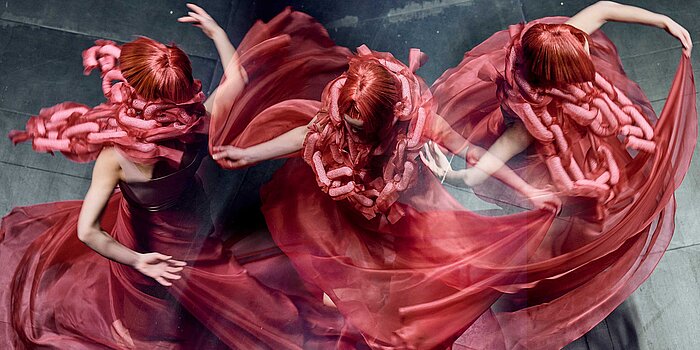 Tančící žena s červenými vlasy a červenými šaty.