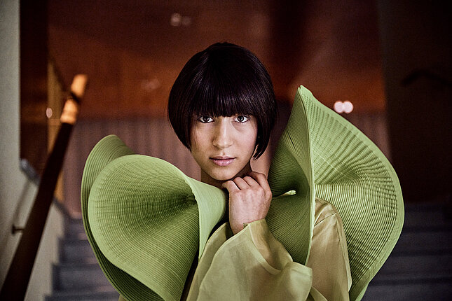 Portrét tanečnice se zeleným futuristickým límcem na šatech.